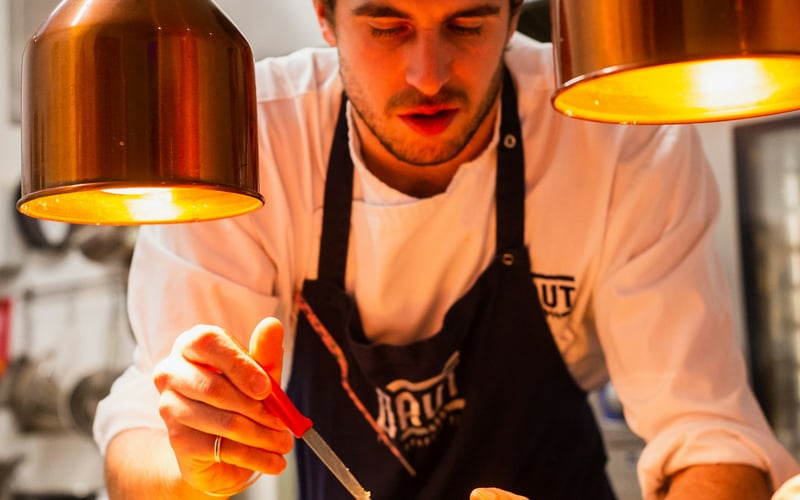 Chef finishing a plate under the pass lights
